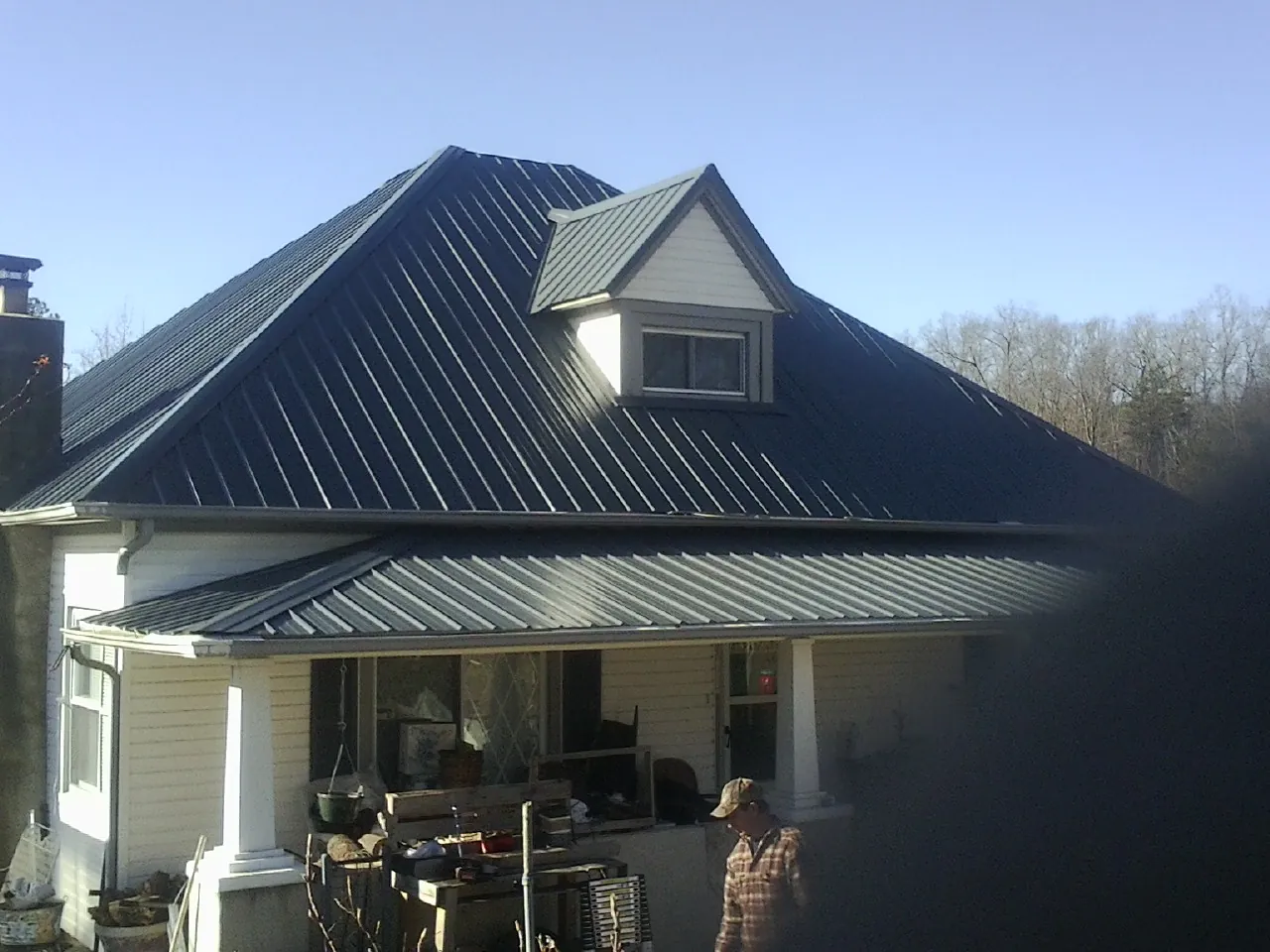 Dark blue standing seam metal roof with a dormer above a front porch in Metter