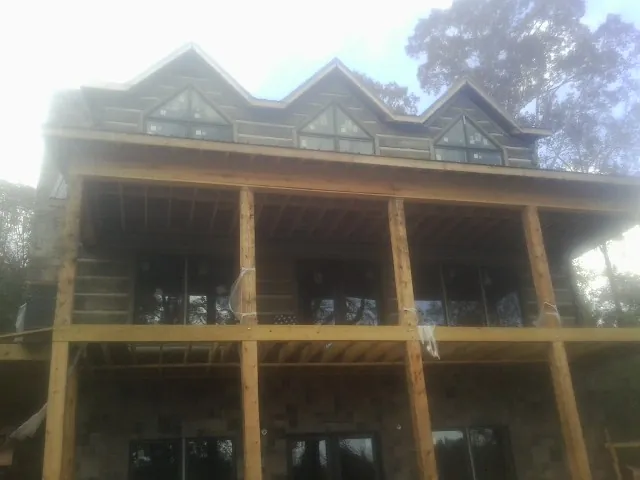 Dormers and porch framing on a large log home under construction — Roof Coating work by our crew in Metter