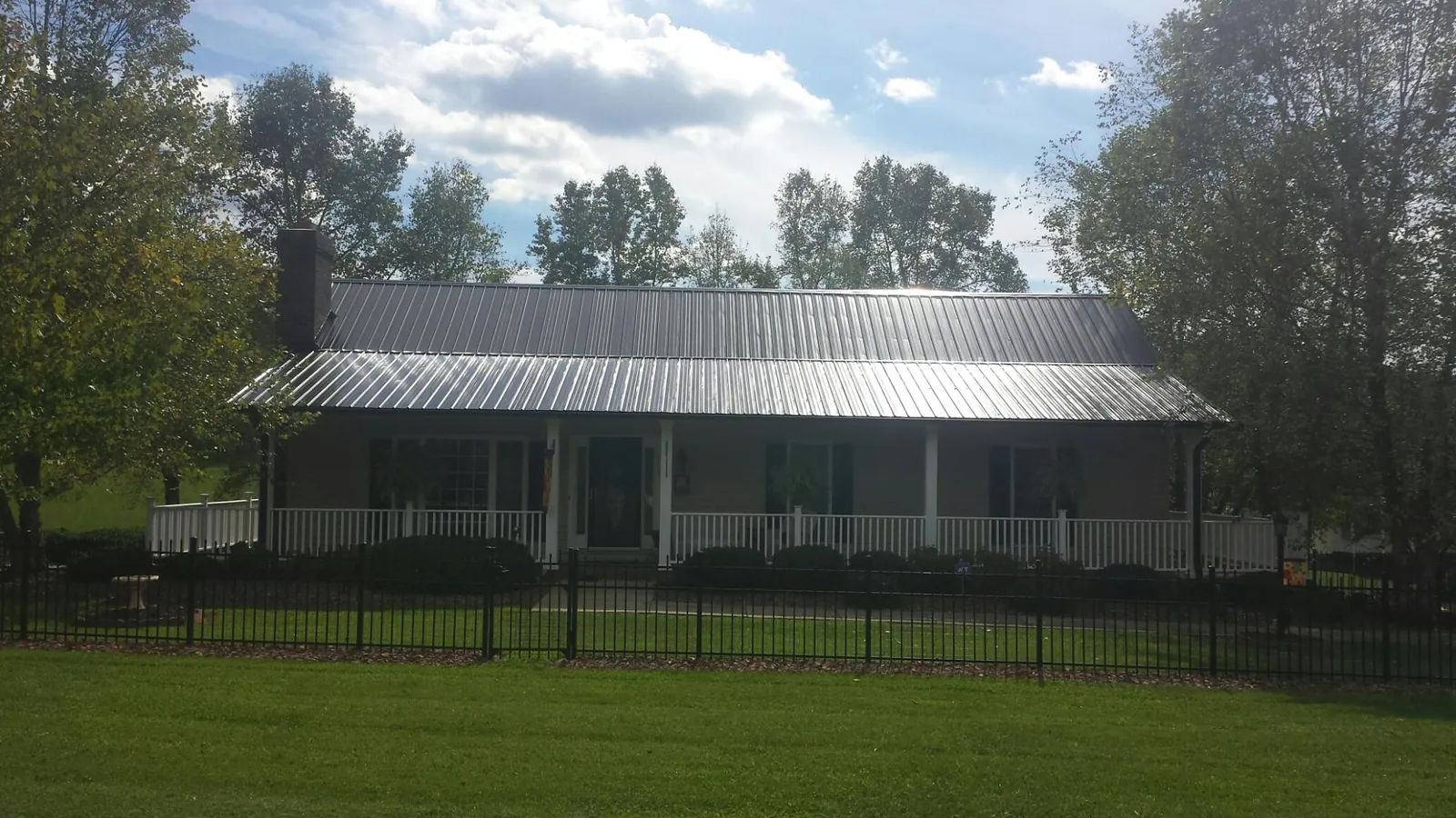 Gray metal roof on a brick ranch with a full width front porch — Gutter Guard Installation work by our crew in Metter