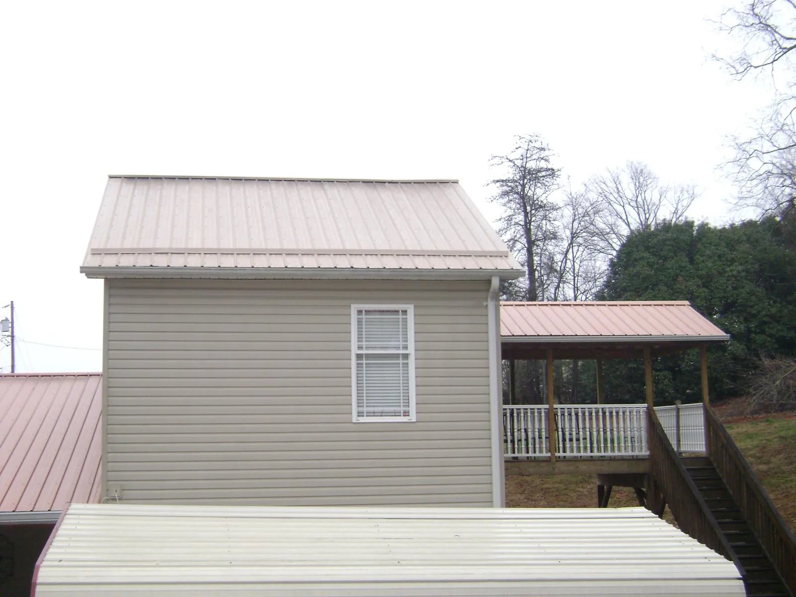 Tan metal roofs on a two story addition and attached porch, from a Roof Replacement job in Metter