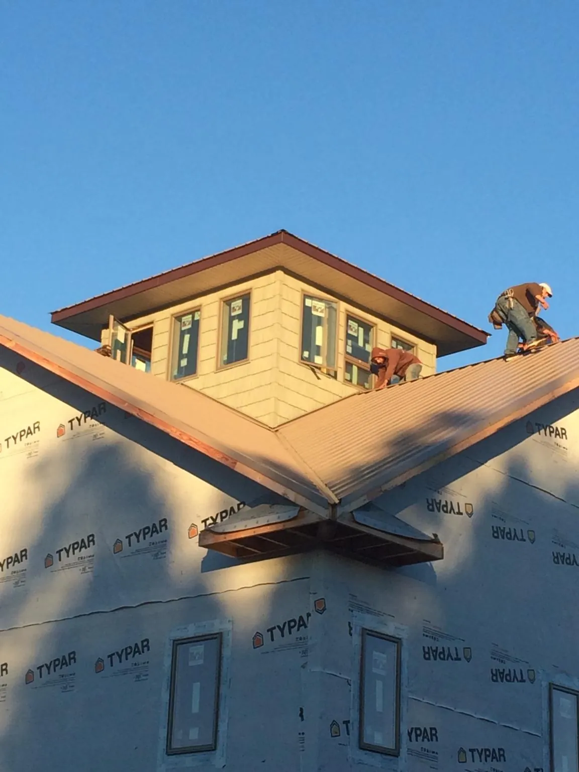 Roofers working around a rooftop cupola on a new metal roof at sunset — Roof Waterproofing in Metter by Roofing Brothers